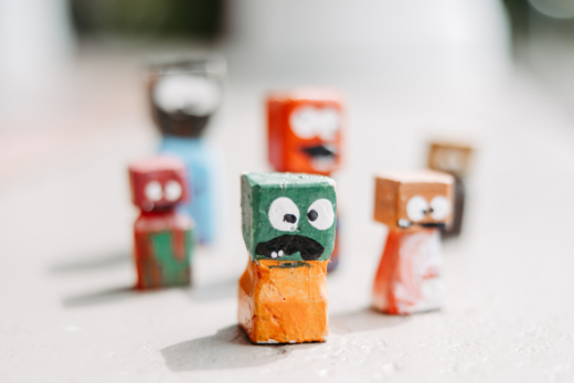 Holzfiguren aus Stücken von Vierkanthölzern. Bunt bemalt mit lustigen Gesichtern und großen Augen.