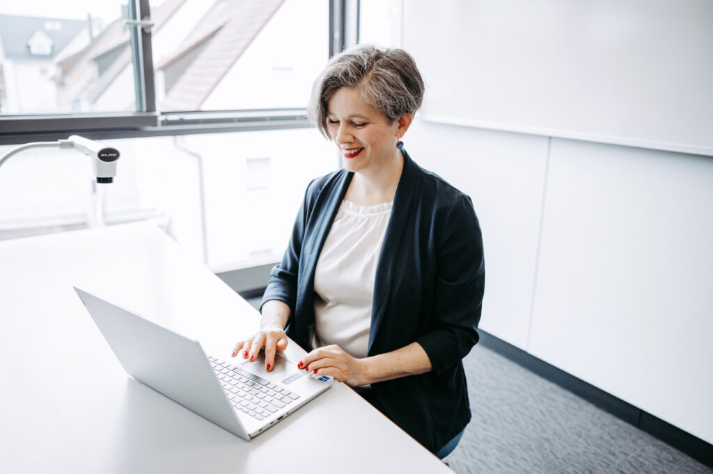 Katrin sitzt am Laptop und tippt.