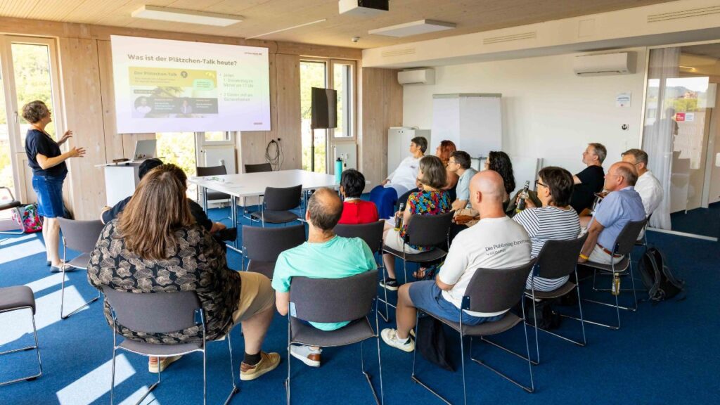 Raum mit rund 15 Personen beim Barcamp Digitale Barrierefreiheit in Tübingen. Katrin zeigt über einen Beamer Details zum Plätzchen-Talk.